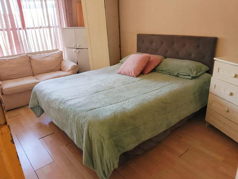 A bedroom featuring laminate flooring and a built-in wardrobe, offering a functional space with natural light from the window.