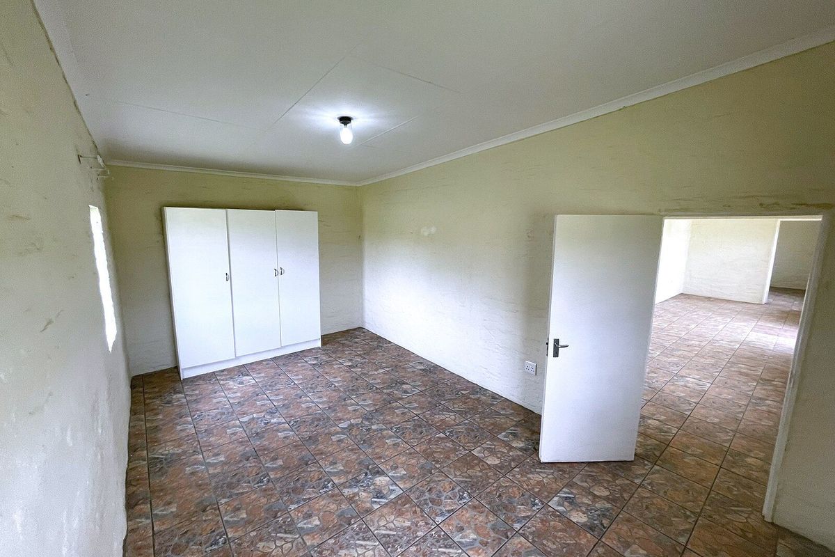 An empty bedroom featuring tiled flooring, a built-in wardrobe, and coved ceilings, presenting a blank canvas for potential renovation or interior design updates.
