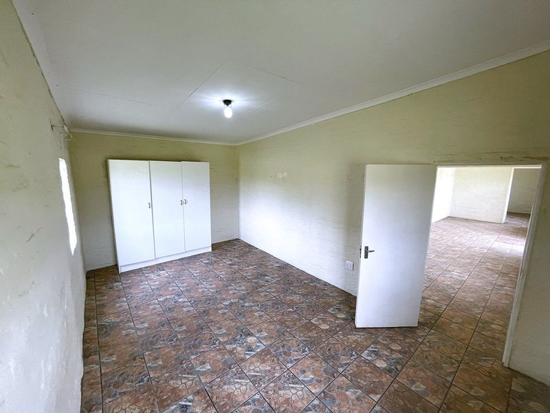 An empty bedroom featuring tiled flooring, a built-in wardrobe, and coved ceilings, presenting a blank canvas for potential renovation or interior design updates.