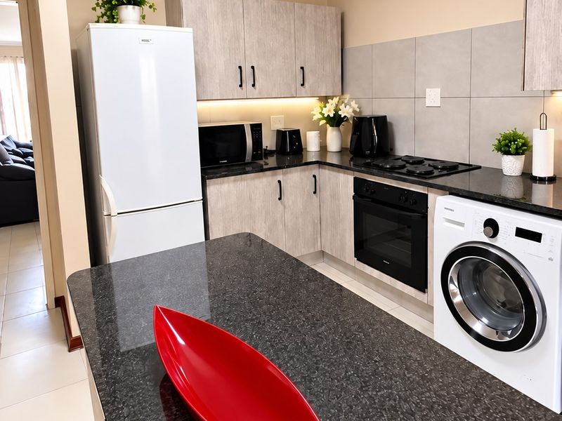 Modern kitchen featuring granite countertops, built-in cabinetry, integrated appliances, and a skylight, providing a functional and well-lit cooking space.