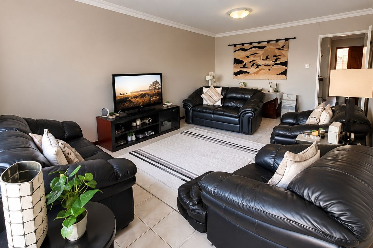 A comfortable living room featuring neutral wall tones, tiled flooring, and classic ceiling cornice detailing, providing a functional and well-maintained space.