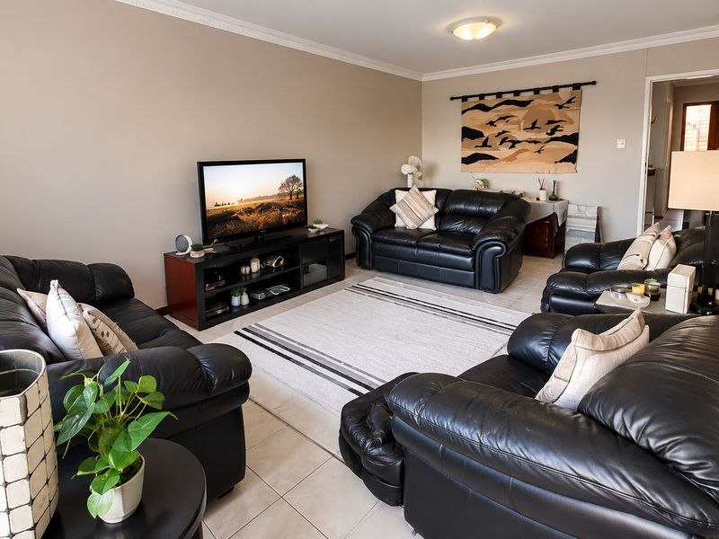A comfortable living room featuring neutral wall tones, tiled flooring, and classic ceiling cornice detailing, providing a functional and well-maintained space.