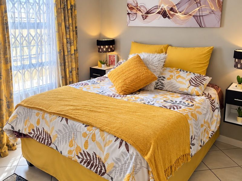 A well-maintained bedroom featuring tiled flooring, a window with a security gate, and built-in bedside tables.