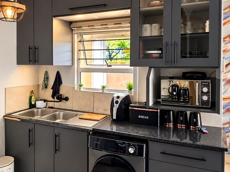 Modern kitchen featuring dark grey cabinetry, granite countertops, a double sink, and integrated appliances with a clean, contemporary finish.