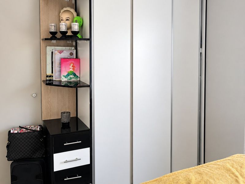 A bedroom featuring a modern built-in sliding door wardrobe with an integrated shelving and drawer unit.