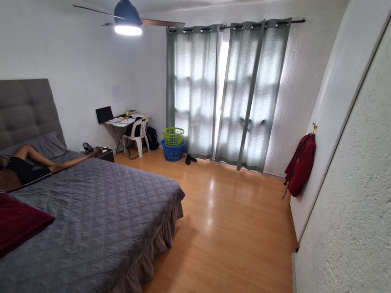 A bedroom featuring laminate flooring, a ceiling fan, and a sliding glass door providing natural light.
