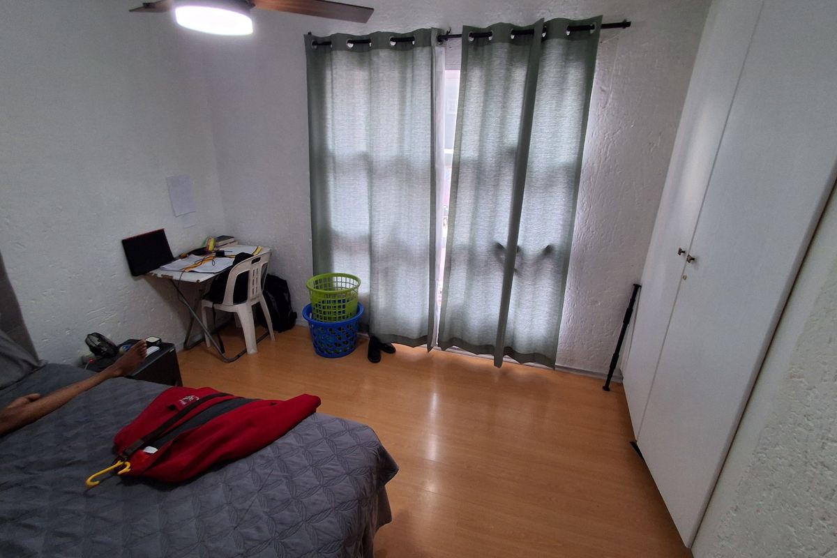 A functional bedroom featuring laminate flooring, a built-in wardrobe, and a ceiling fan, providing a practical living space.