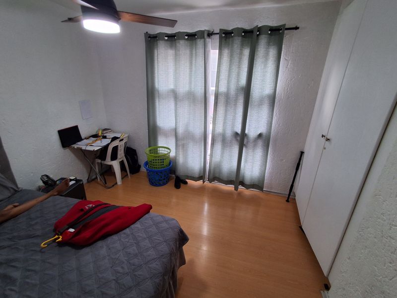 A functional bedroom featuring laminate flooring, a built-in wardrobe, and a ceiling fan, providing a practical living space.
