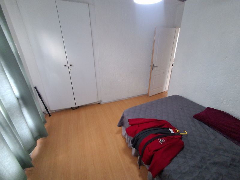 A functional bedroom featuring laminate flooring and a built-in wardrobe, providing essential storage space within the apartment.