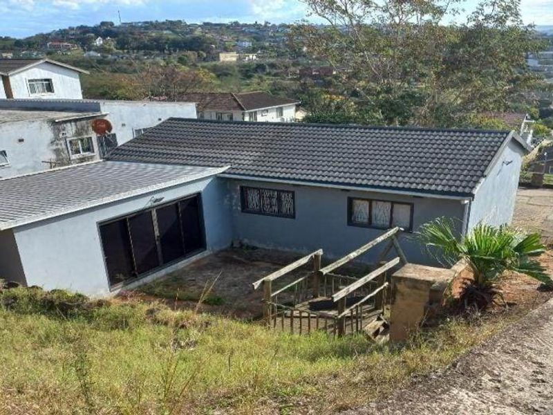 Rear view of the property featuring a tiled roof, sliding glass doors, and an elevated wooden staircase leading to the backyard area.