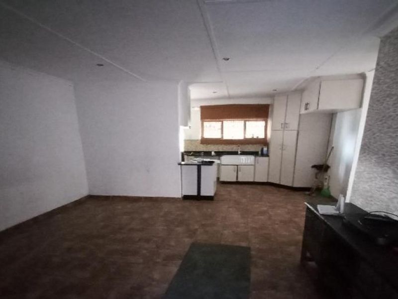 Open plan living and kitchen area featuring tiled flooring, built-in cabinetry, and a central kitchen island, offering a functional layout for daily living.