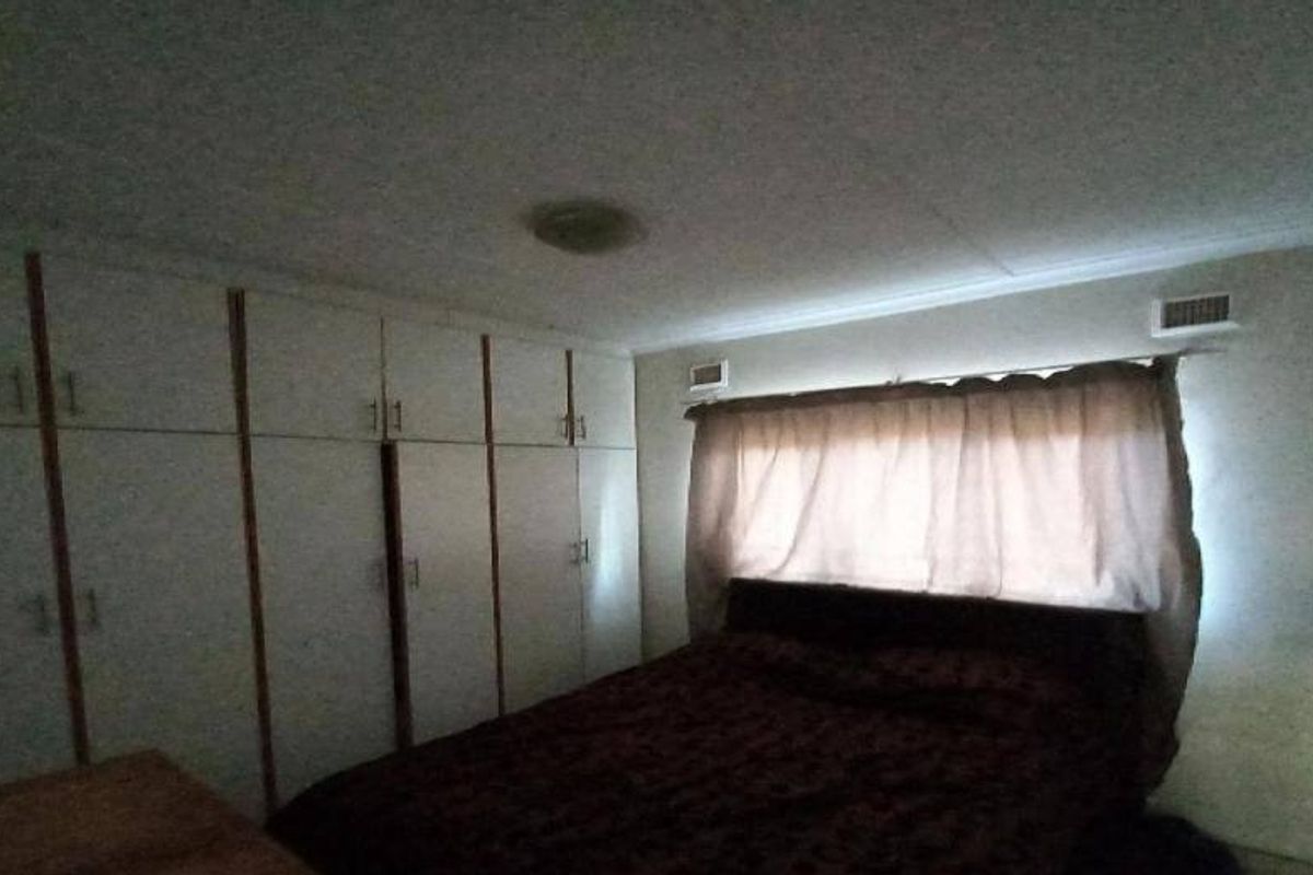 A bedroom featuring extensive built-in cupboards and an integrated air conditioning vent, providing functional storage and climate control.