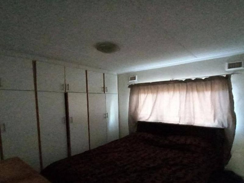 A bedroom featuring extensive built-in cupboards and an integrated air conditioning vent, providing functional storage and climate control.