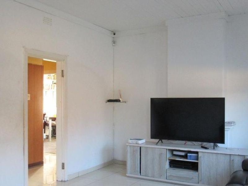 A living room area featuring tiled flooring and a timber ceiling, requiring cosmetic updates to improve the overall aesthetic.