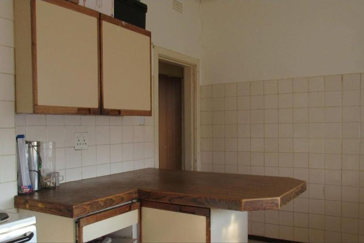 A dated kitchen featuring original cabinetry, tiled splashbacks, and a laminate countertop, offering significant potential for a modern renovation.