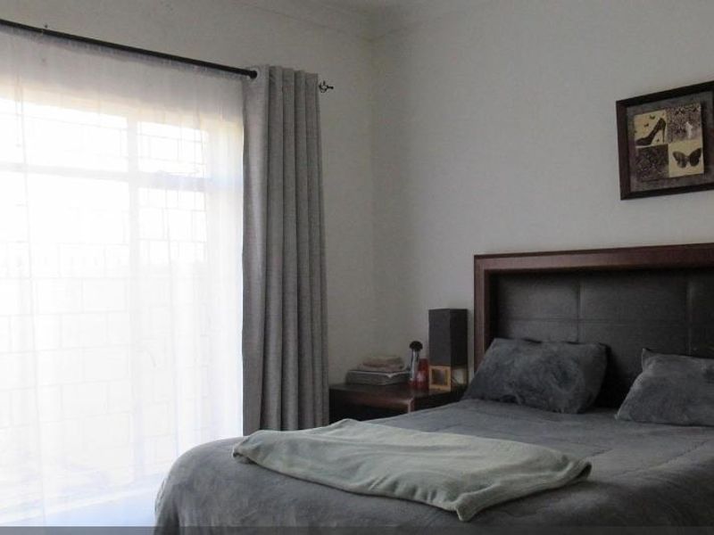 A bedroom featuring a large sliding glass door with security gate and curtain rail, providing natural light and access to the exterior.