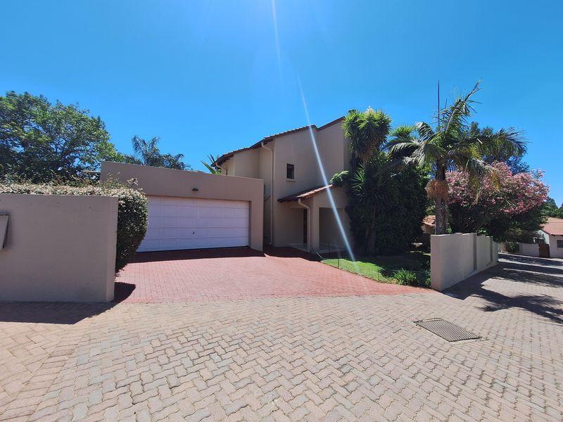 Front elevation of a townhouse featuring a paved driveway, double garage, and established garden boundary walls.