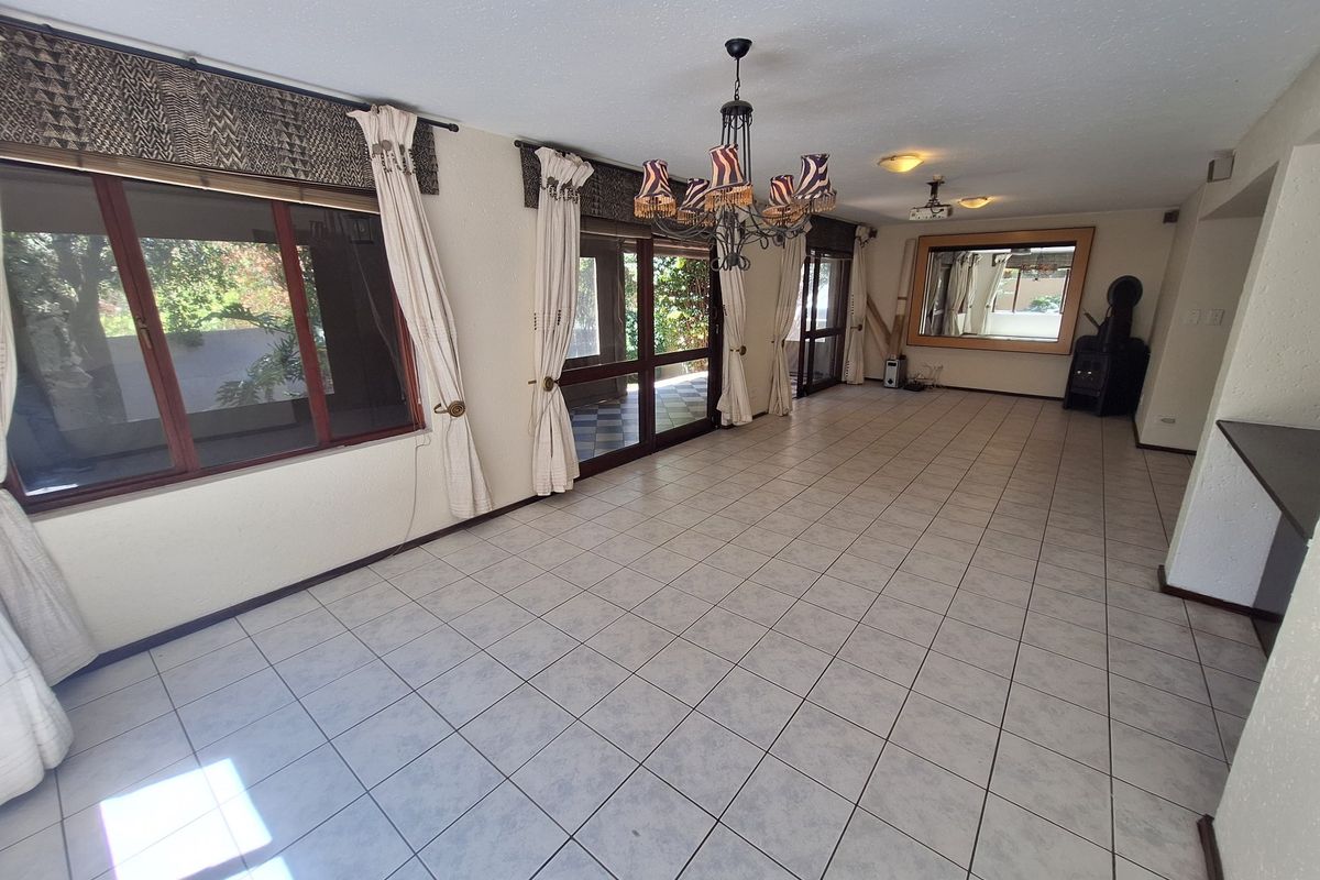 Spacious open-plan living area featuring tiled flooring, a wood-burning fireplace, and large sliding glass doors providing access to the outdoor space.