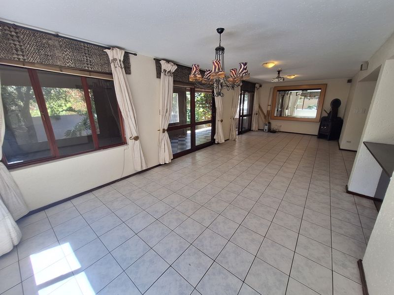 Spacious open-plan living area featuring tiled flooring, a wood-burning fireplace, and large sliding glass doors providing access to the outdoor space.