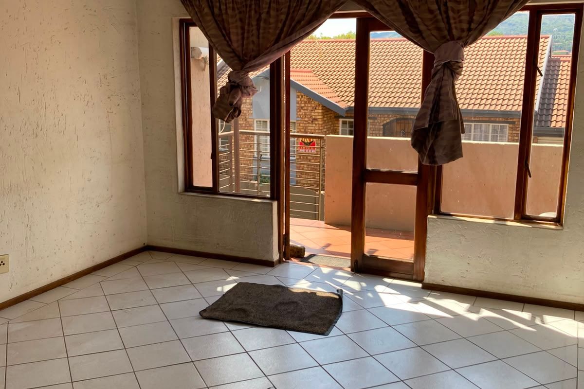 An empty living room featuring tiled flooring and a sliding glass door leading to an outdoor balcony area.