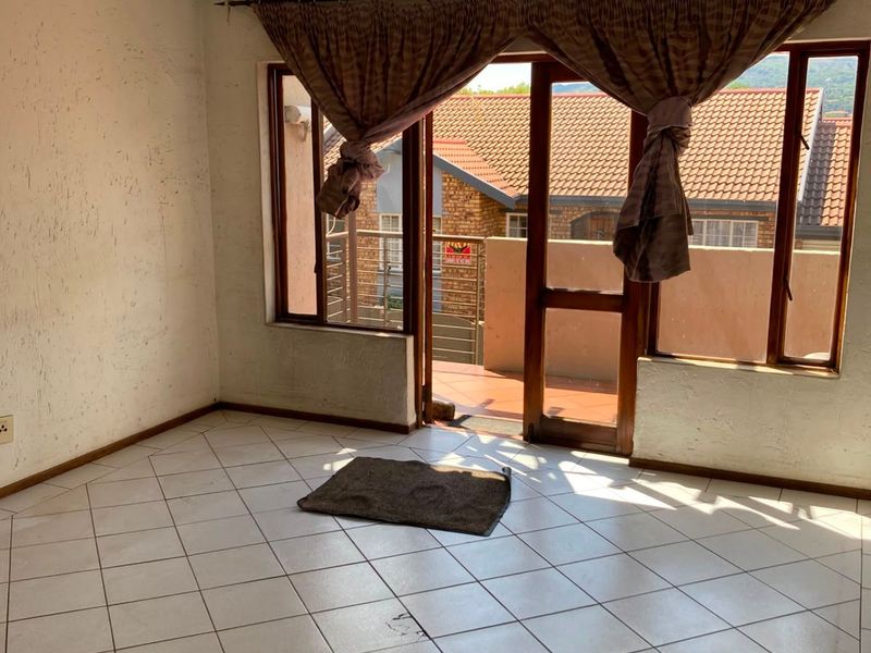 An empty living room featuring tiled flooring and a sliding glass door leading to an outdoor balcony area.