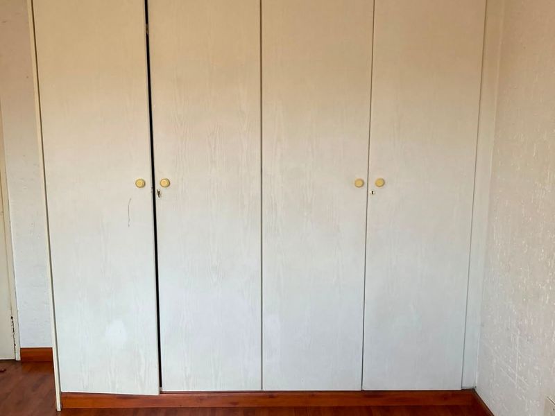 A bedroom featuring built-in cupboards with laminate flooring and standard finishes.