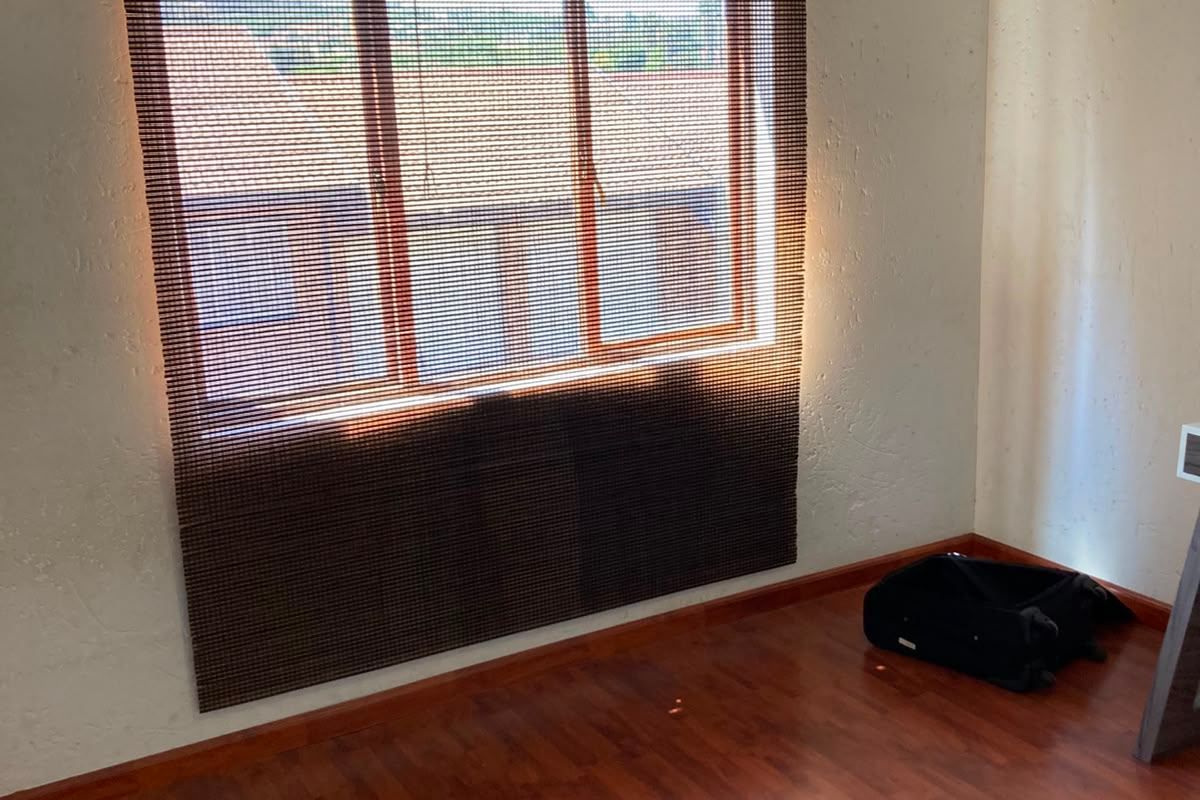 A vacant bedroom featuring laminate flooring and a window with a wooden frame, offering a blank canvas for personalization.