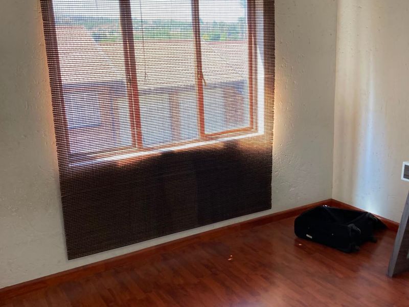 A vacant bedroom featuring laminate flooring and a window with a wooden frame, offering a blank canvas for personalization.