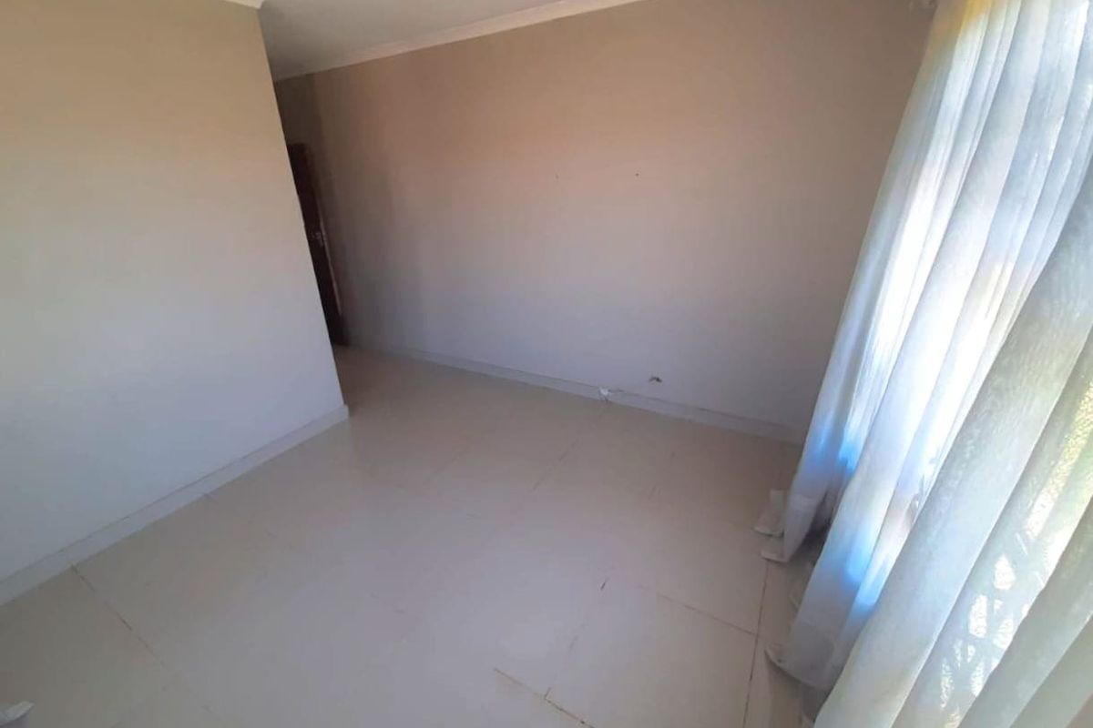 A vacant bedroom featuring neutral wall tones, tiled flooring, and coved ceiling details, offering a clean and versatile space ready for personalization.