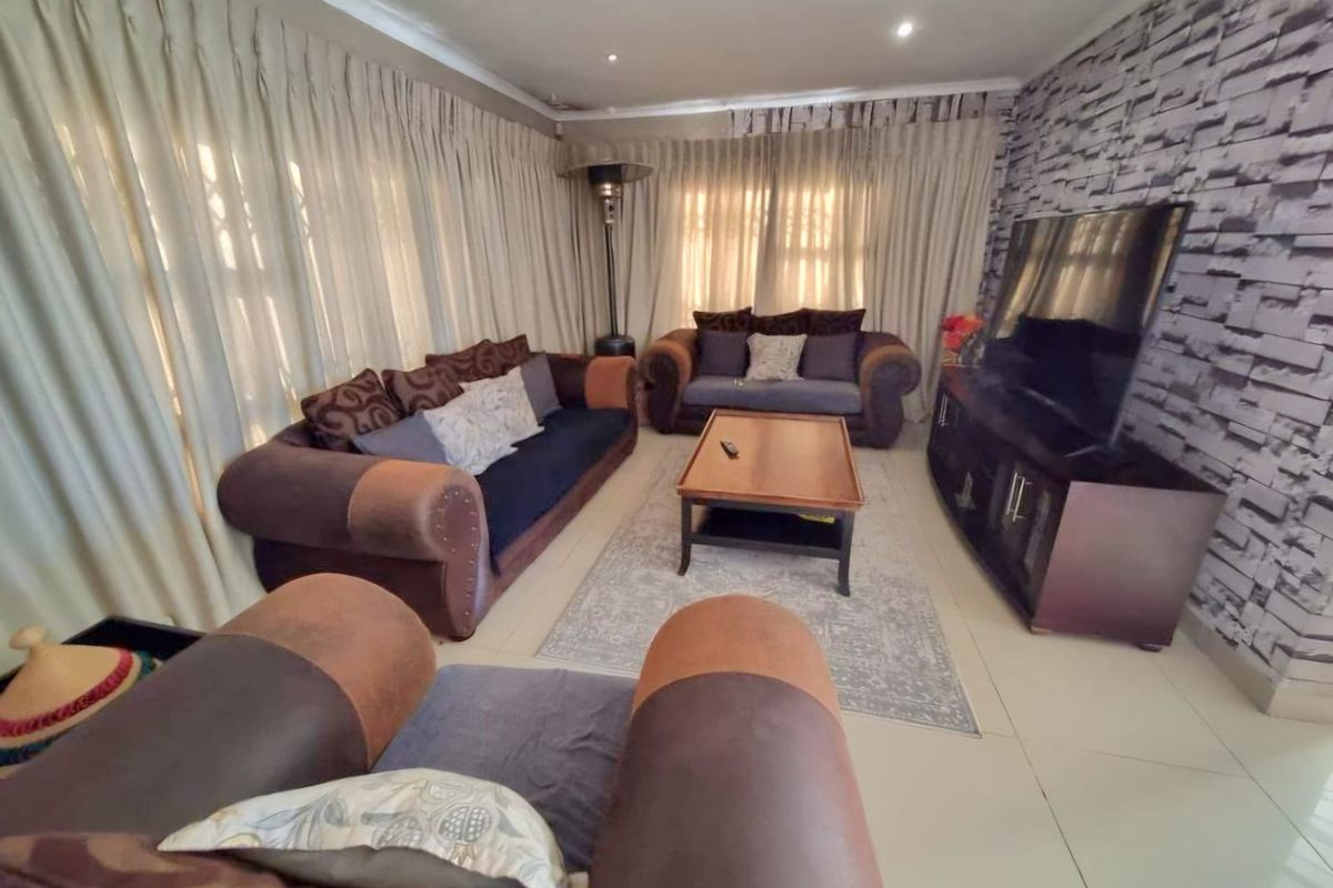 A comfortable living room featuring tiled flooring, recessed lighting, and a textured feature wall, providing a functional space for relaxation.