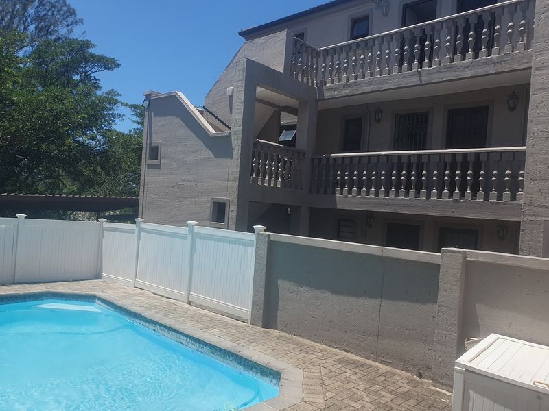 Exterior view of the apartment complex featuring a swimming pool, paved surround, and multi-level balconies with traditional balustrades.