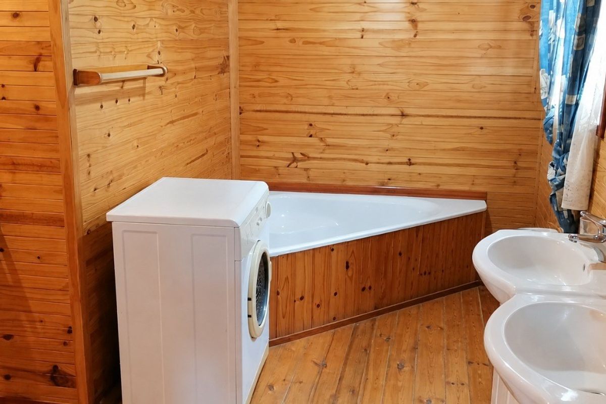 Bathroom featuring timber wall cladding and flooring, a corner bathtub, and a double vanity unit.