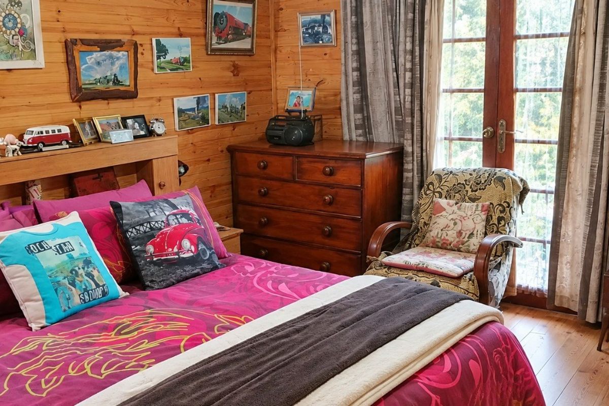 A cozy bedroom featuring warm timber wall paneling, wooden flooring, and classic french doors that provide natural light and outdoor access.
