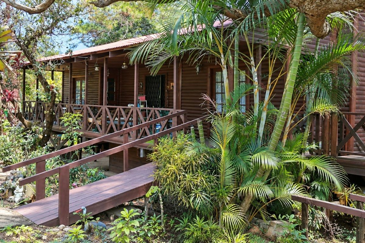 A rustic timber townhouse featuring a wrap-around deck, accessible ramp, and lush garden surroundings, showcasing a natural and integrated outdoor living space.