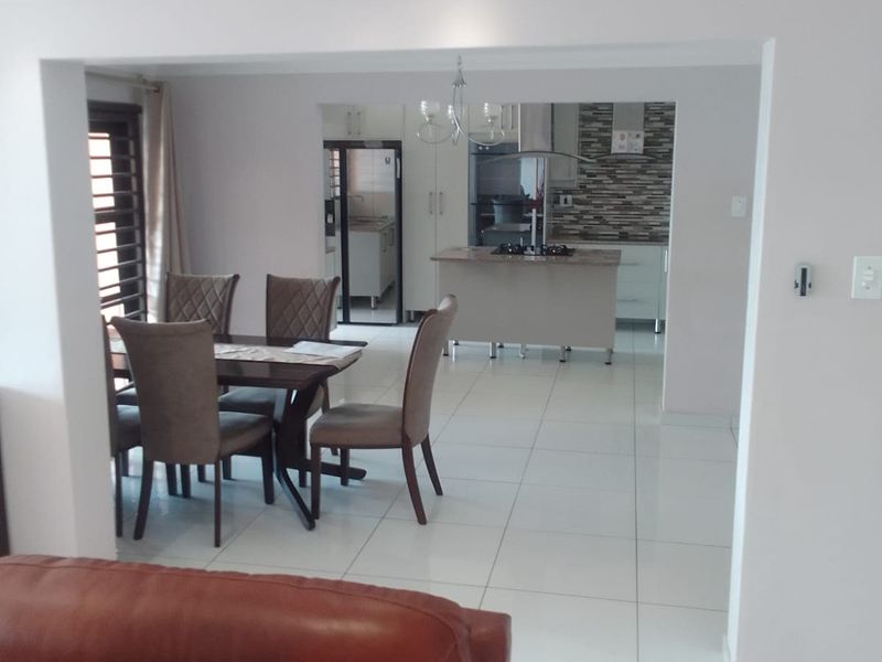 Open plan living and dining area featuring tiled floors, recessed lighting, and a modern kitchen with a central island and built-in hob.