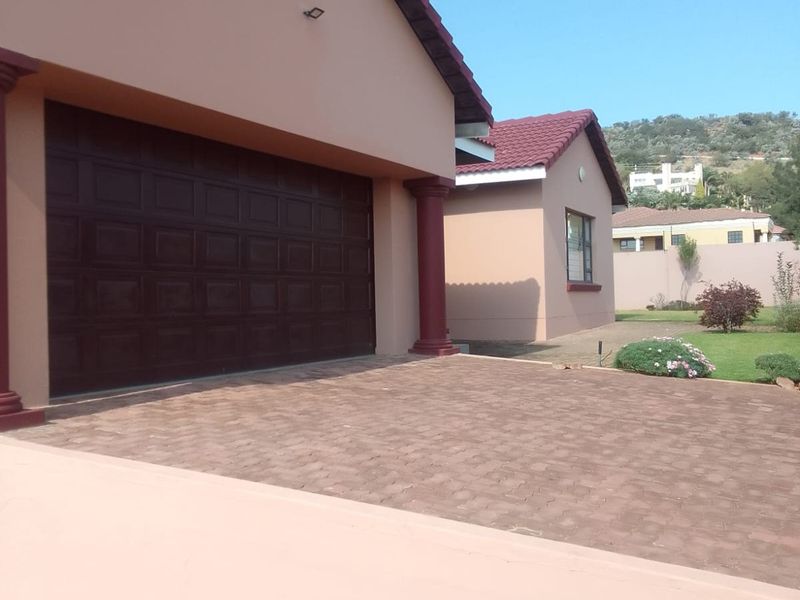 Front view of the property featuring a double garage, paved driveway, and well-maintained exterior facade with decorative columns.