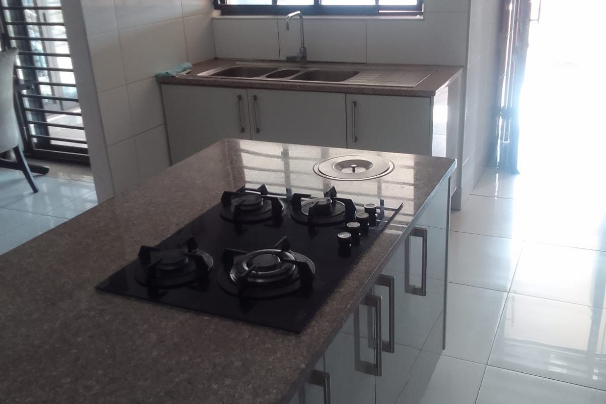 Modern kitchen featuring a central island with a built-in gas cooktop, extractor fan, double sink, and tiled finishes throughout.