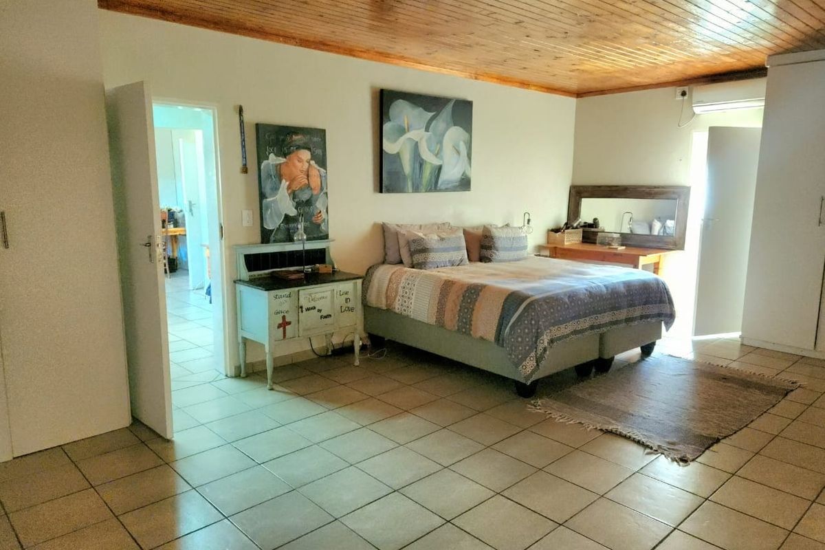 Spacious bedroom featuring ceramic floor tiles, a timber tongue and groove ceiling, and a wall-mounted air conditioning unit.