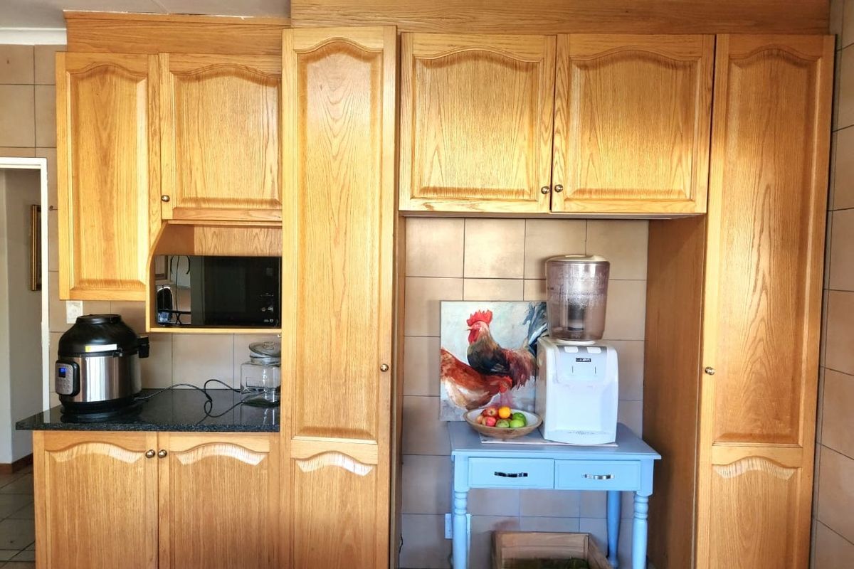 A kitchen area featuring traditional oak cabinetry, granite countertops, and a tiled backsplash, offering a classic aesthetic with functional storage space.