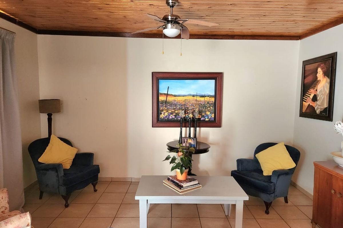 A cozy living room featuring a warm timber-paneled ceiling, a central ceiling fan, and neutral tiled flooring.