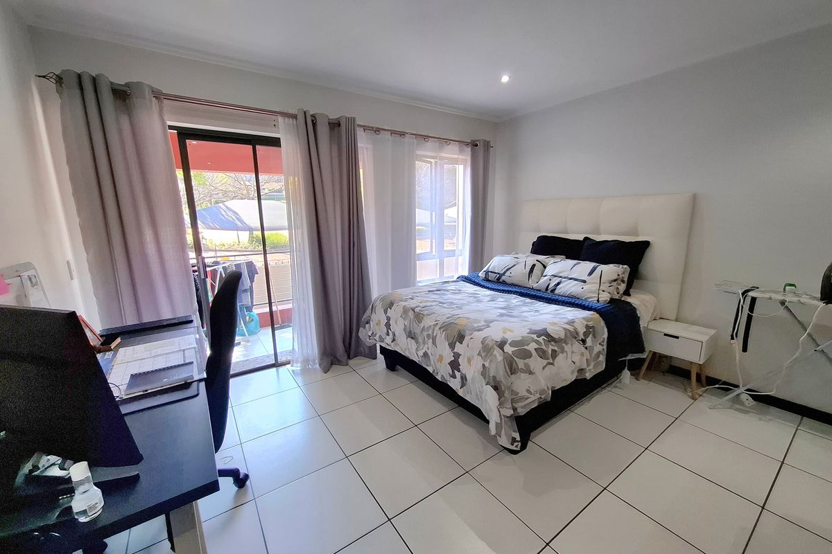 A bright bedroom featuring tiled flooring, recessed downlighting, and a sliding glass door providing direct access to an outdoor balcony area.