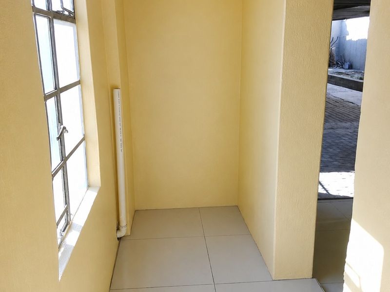 A functional utility space featuring tiled flooring, a steel-framed window, and an accessible electrical distribution board.