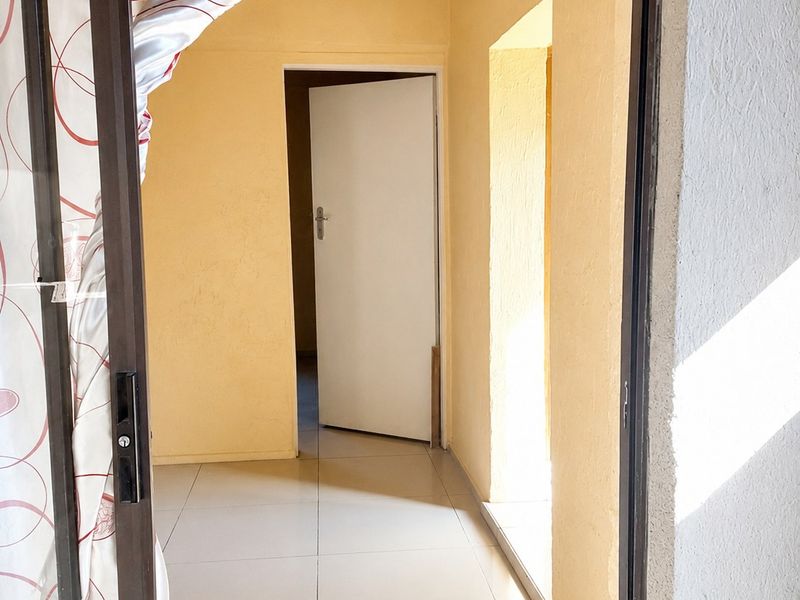 A vacant hallway featuring neutral tiled flooring and access to adjacent rooms through internal doorways.