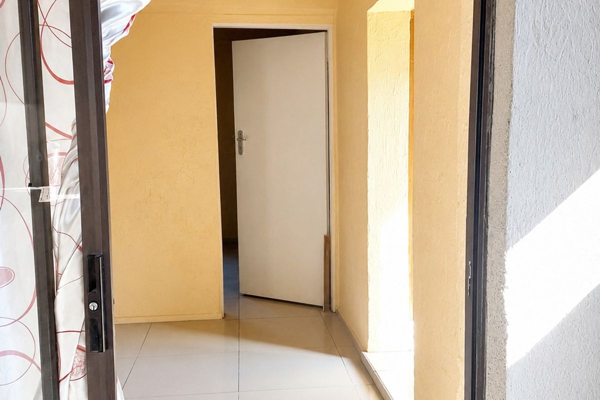 A vacant hallway featuring neutral tiled flooring and access to adjacent rooms through internal doorways.