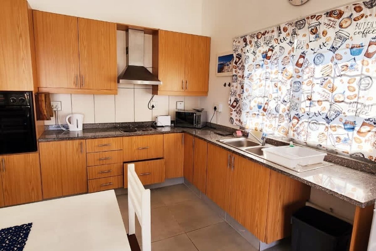 A functional kitchen featuring wooden cabinetry, granite countertops, a built-in oven, and an extractor fan, providing a practical workspace for daily cooking.