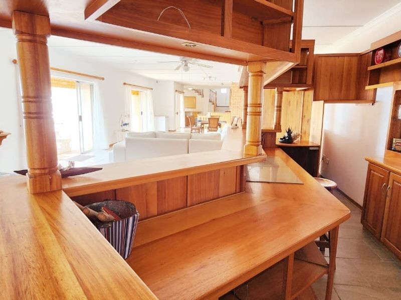 Open plan living area featuring extensive wooden cabinetry, a breakfast bar, and tiled flooring, connecting the kitchen to the main living space.