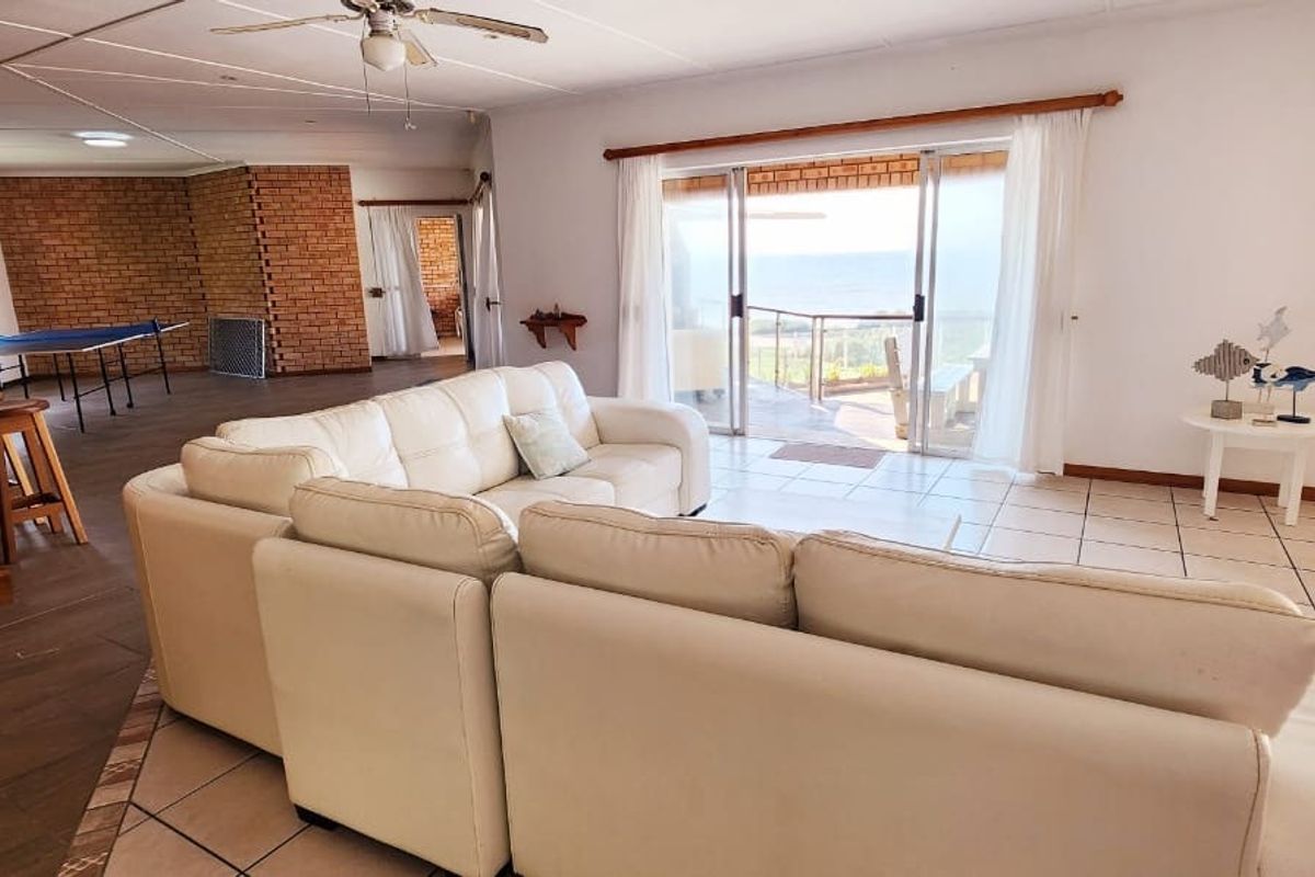 Spacious living area featuring tiled floors, an exposed brick wall, a built-in bar, and sliding glass doors leading to an outdoor patio with views.