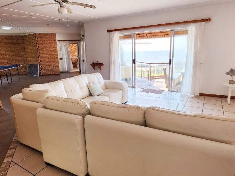 Spacious living area featuring tiled floors, an exposed brick wall, a built-in bar, and sliding glass doors leading to an outdoor patio with views.