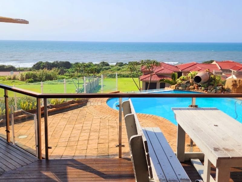 Elevated timber balcony overlooking a private swimming pool and landscaped garden with expansive ocean views.