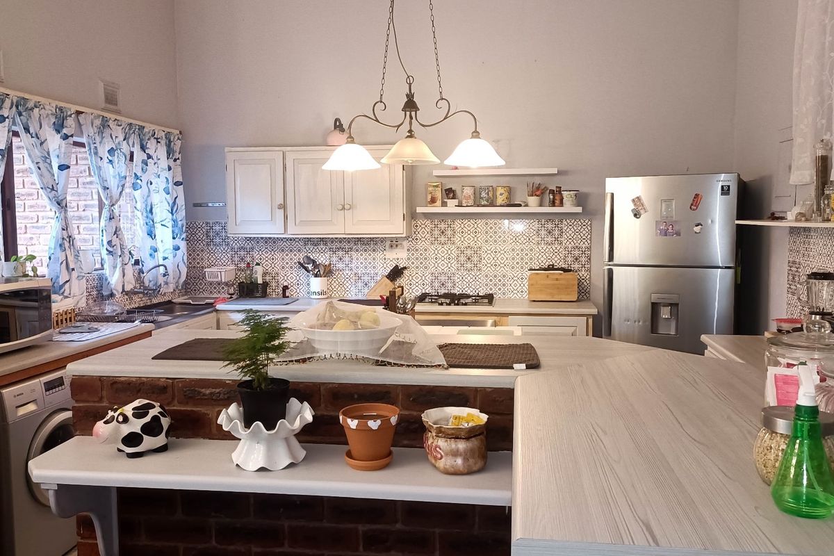 A functional kitchen featuring a breakfast bar with brick detailing, patterned tiled backsplash, built-in cabinetry, and a gas hob.